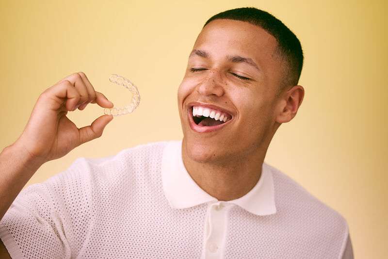 [CRO] Man - Smile - Mouth open - Hand - Aligner - White Shirt - Closed eyes - Yellow Background - Desktop