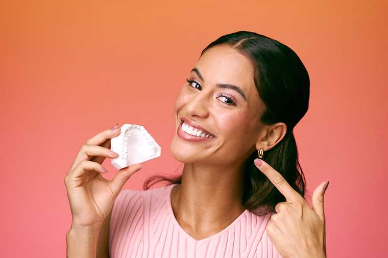 [CRO] Women - Brunette - Pink - Dental Arch - Looking right - Finger - Hand - Smile - Orange - Gradient - Background - Desktop