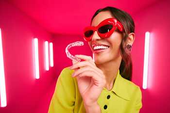 [CRO] Women - Brunette - Green - Shirt - Red Glasses - Aligners - Pink - Light - Background - Mobile