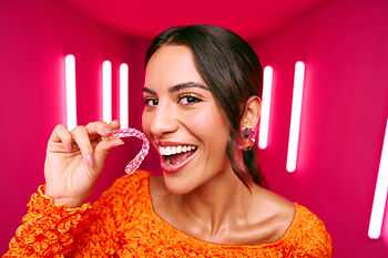 [CRO] Women - Brunette - Orange - Long sleeve - Aligners - Looking left - Pink - Light - Background - Mobile